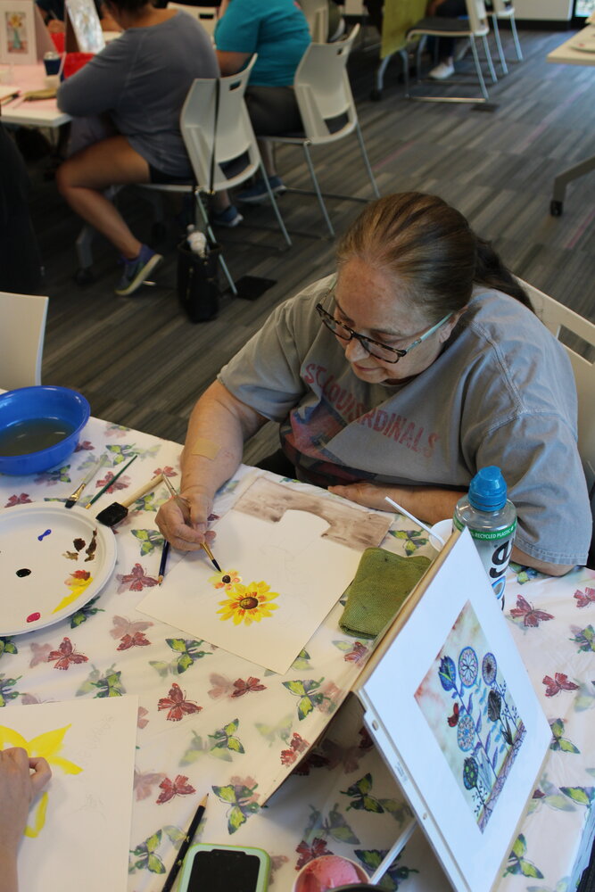Lee Bortz works on her sunflower as she paints her watercolor design.