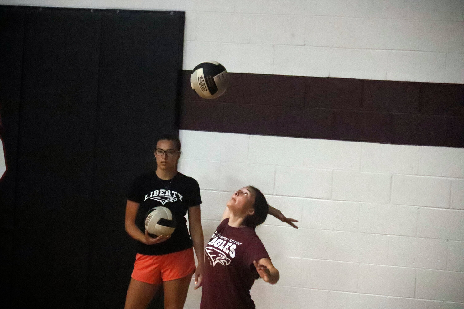 Raelee Bruno (right) practices her serve as assistant coach Gracie Foran looks on.
