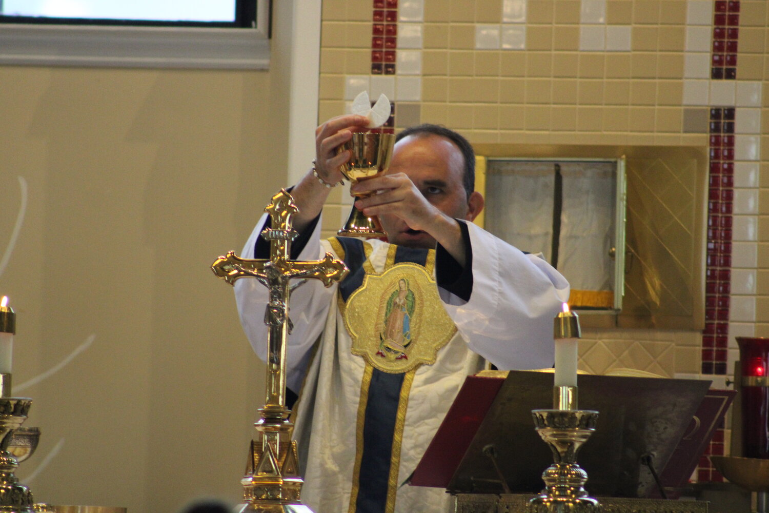 Father Eddie prepares the Eucharist during the Aug. 22 Mass at Holy Rosary.