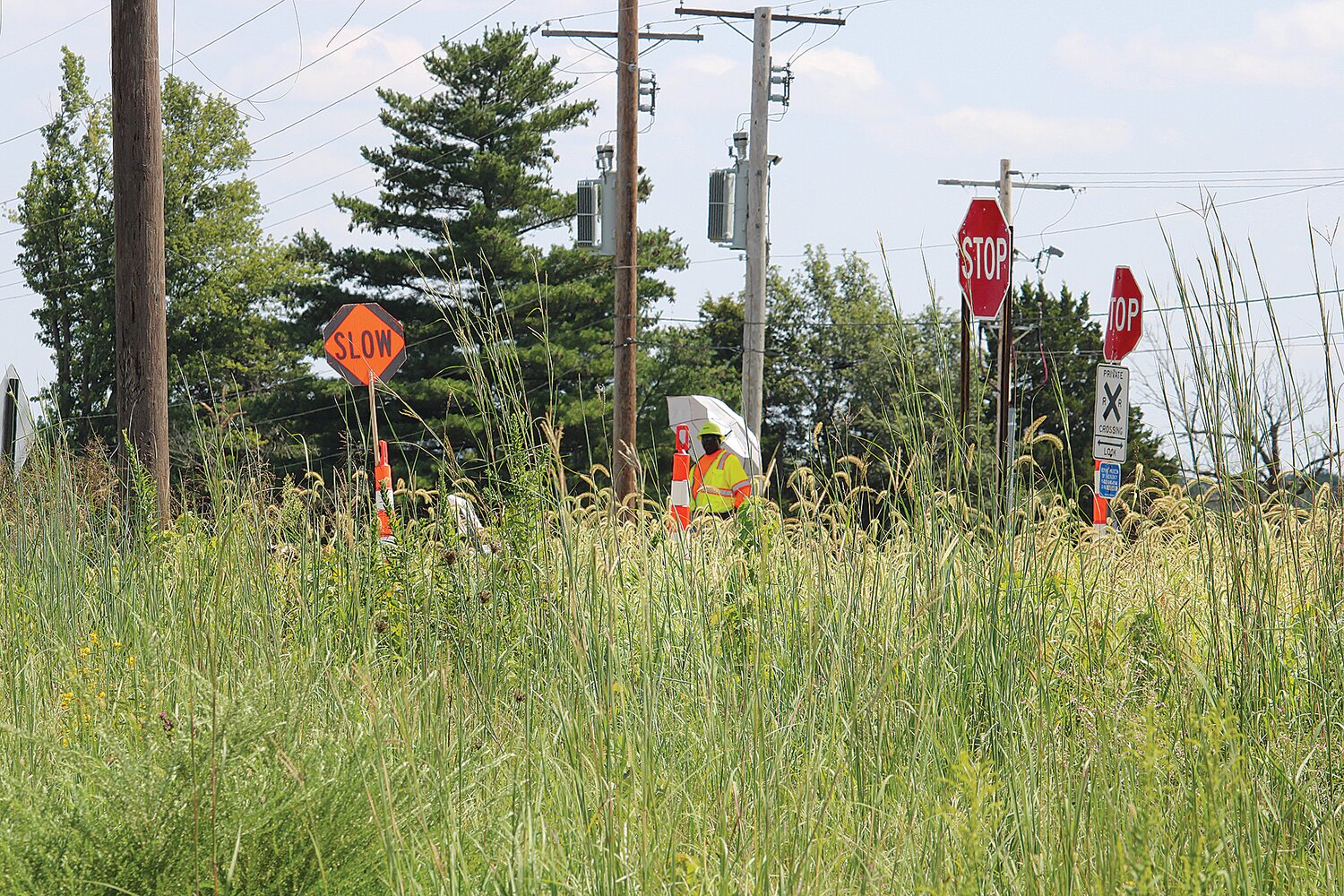 A flagger stands at the railroad crossing just to the east of Archer Road. Flaggers were added to the two crossings near the new AFG plant after three accidents occurred, including one fatal, since December 2022.