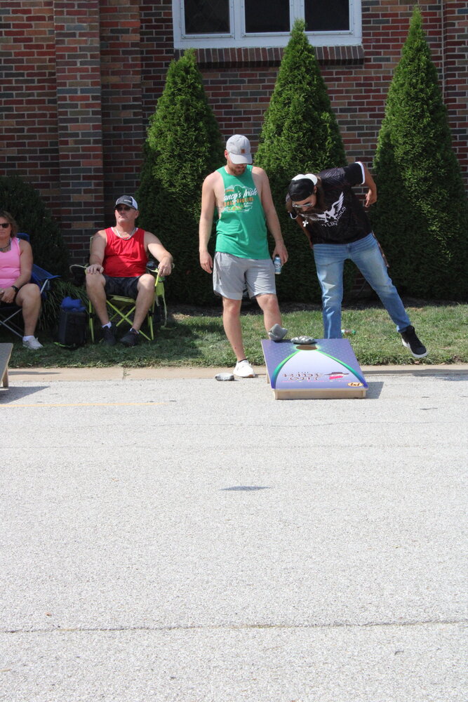Two cornhole tournament participants watch as a bag lands.