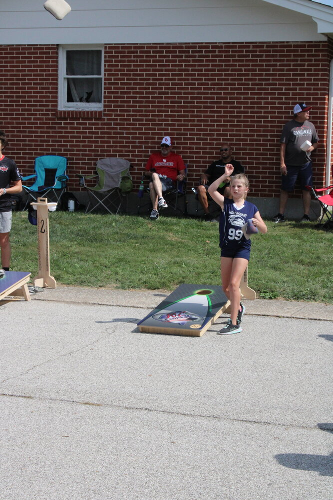A young girl tosses a bag during the cornhole tournament.
