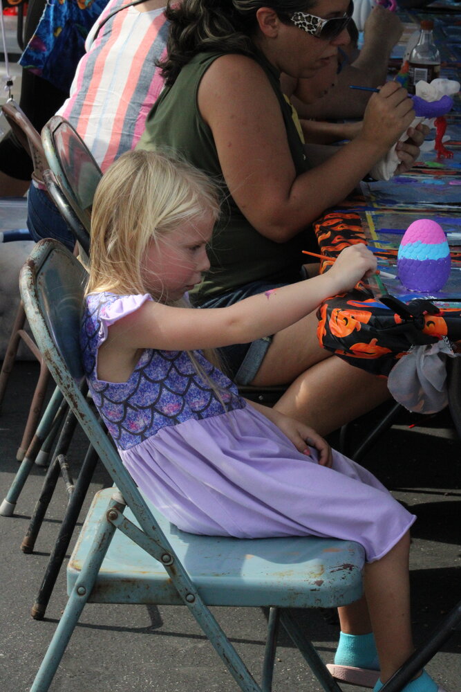 A girl paints an egg in the children's section of the Fall Festival.