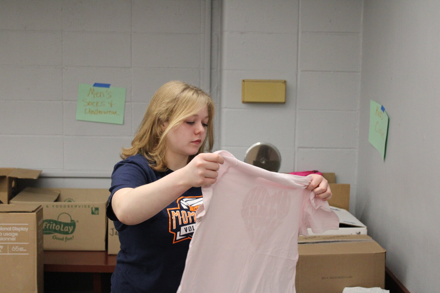 Wentzville Middle School Student Council President Sophia Sexton looks at a donated shirt as she sorts items that will be donated to help homeless veterans.