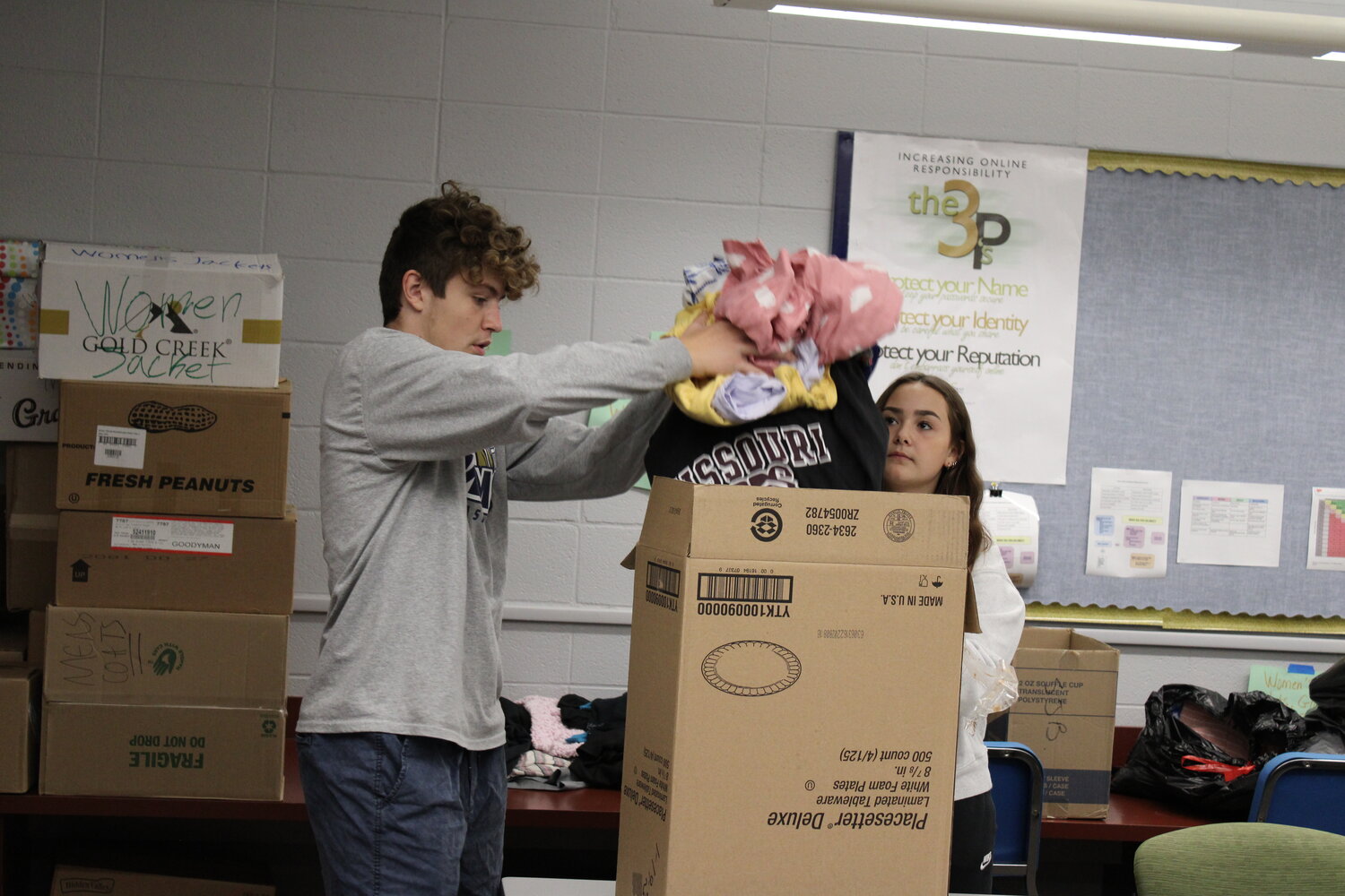 Logan Van Scoy loads a box with donations while McKenzie Fry helps.