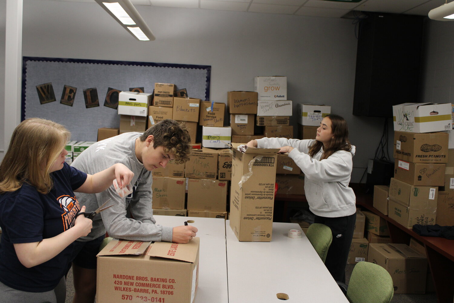 Sophia Sexton, Logan Van Scoy, and McKenzie Fry work to prepare boxes of donations for homeless veterans.
