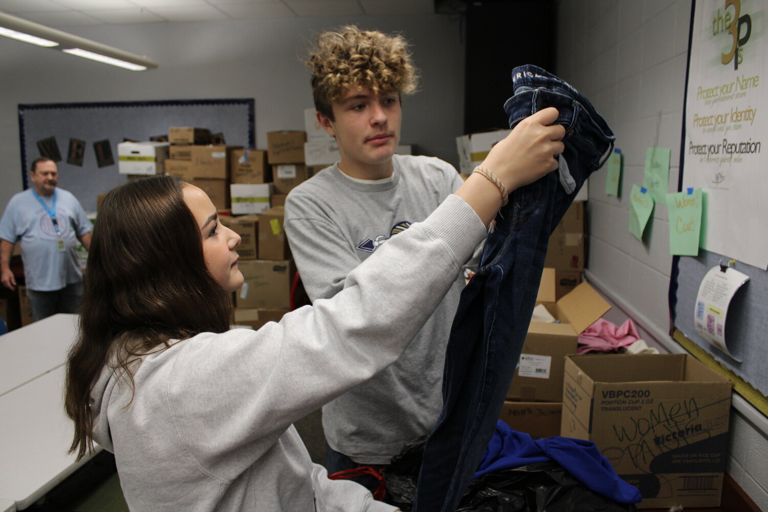Wentzville Middle School students McKenzie Fry and Logan Van Scoy pull a pair of blue jeans from a bag Nov. 17 as they sort through a donation of clothes for homeless veterans as Truesdale mayor and middle school student council sponsor Jerry Cannon watches from the background.
