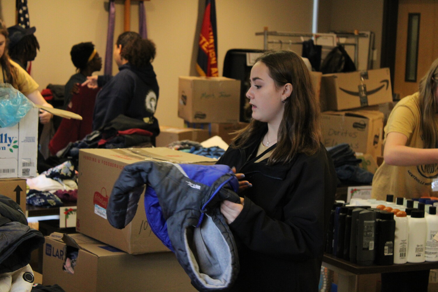 McKenzie Fry holds one of the coats donated as she prepares to place it in its proper location so it can be collected by a homeless individual later that morning.