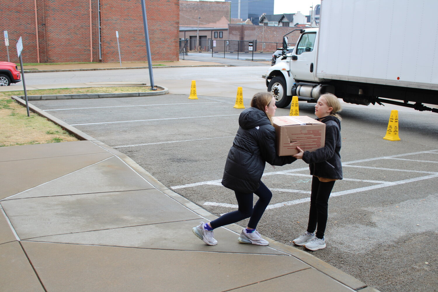 Two students help unload a box of donations. The students used a chain to help move all the donated items from the parking lot to the building.
