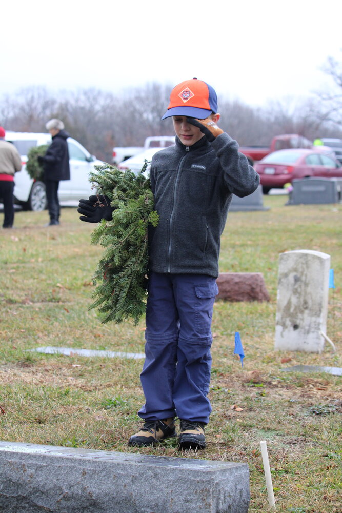 Easton Woldanski salutes a veteran's grave before laying a wreath to honor the individual for his service.