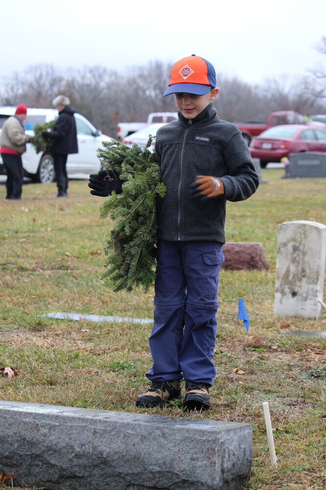 Easton Woldanski prepares to lay a wreath to honor a veteran at the Warrenton City Cemetery.