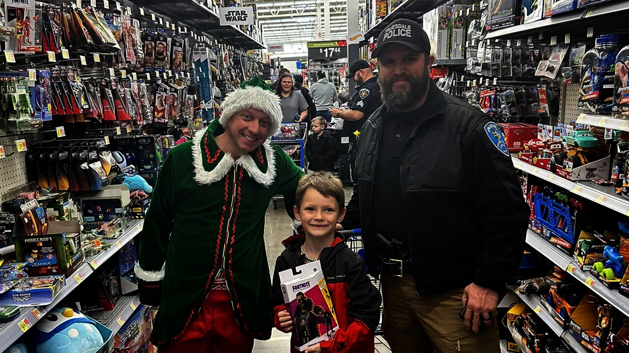 Truesdale Police Chief Casey Doyle, right, stands with a child during the department's Shop With A Cop event earlier this month.
