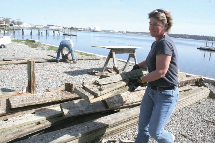 CUT UP DOCK: Sue Toland helps load a dumpster with the remnants of a dock that is being replaced.
