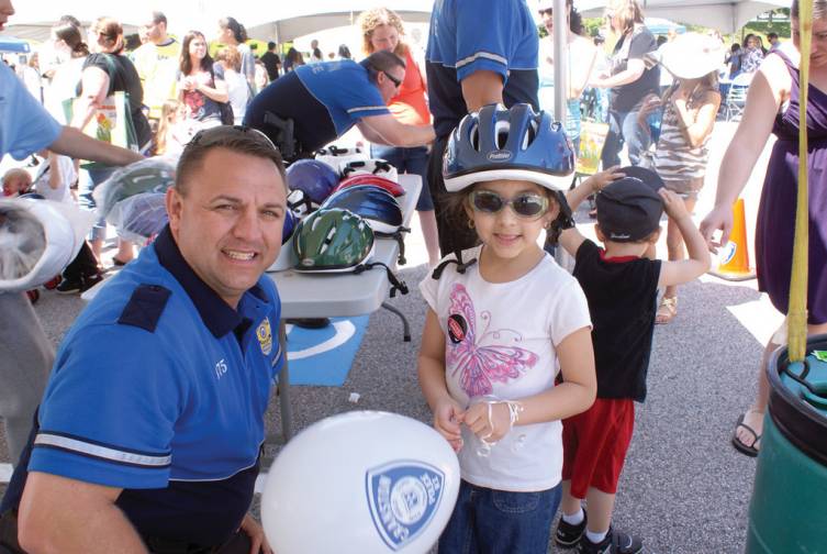 PERFECT FIT: The first 500 children to arrive at Cranston Family Safety Day received free bicycle helmets. Pictured is School Resource Officer Matt Davis fitting 6-year-old Aaliyah Delgado with a new bicycle helmet.