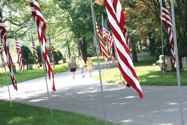 In keeping with tradition, Pawtuxet Memorial Park displayed more than 300 flags bearing the names of veterans buried at the cemetery in a salute to Memorial Day. Taking in the solitude and reverance of the occasion (from left) are Paula Clark, Mariah Hunt and Kayley Hollingshead.