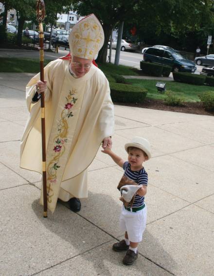 Two-year-old William Quattrucci of Johnston, a parishioner of St. Rocco Church, welcomes Auxiliary Bishop Robert C. Evans to the church during Sunday&rsquo;s procession. Bishop Evans was the main celebrant at the 11 a.m. mass in honor of the Feast of St. Rocco.
