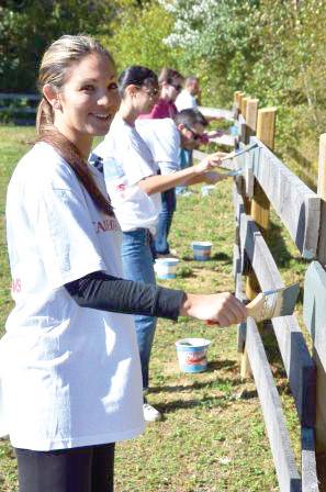 NEW PAINT JOB: Alisha Procaccini from CVS paints a fence at the Lend A Hand Therapeutic Riding facility.