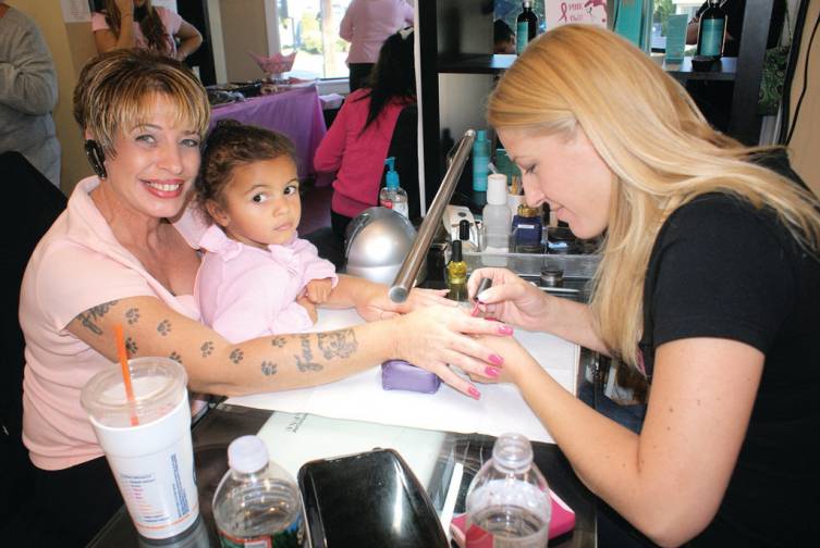 LET THE PINK SHINE: Gina Sylvestro, owner of Gel Essentialz, paints a pretty pink on LaDonna Starbeck, holding young Ariel Lietar.