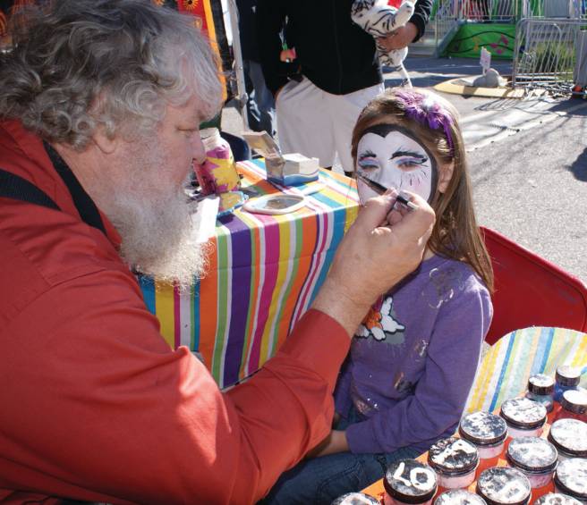 MYSTERIOUS FACE: Face painting artist Marc Kohler demonstrates his artistic ability on the face of 6-year-old Isabella Brown, a student at Immaculate Conception.