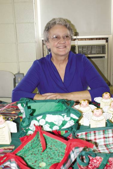 MADE WITH LOVE: Gerie DeAngelis sits at a table of handmade items including placemats, potholders and other household items for sale at the Woodridge Church Holiday Bazaar.