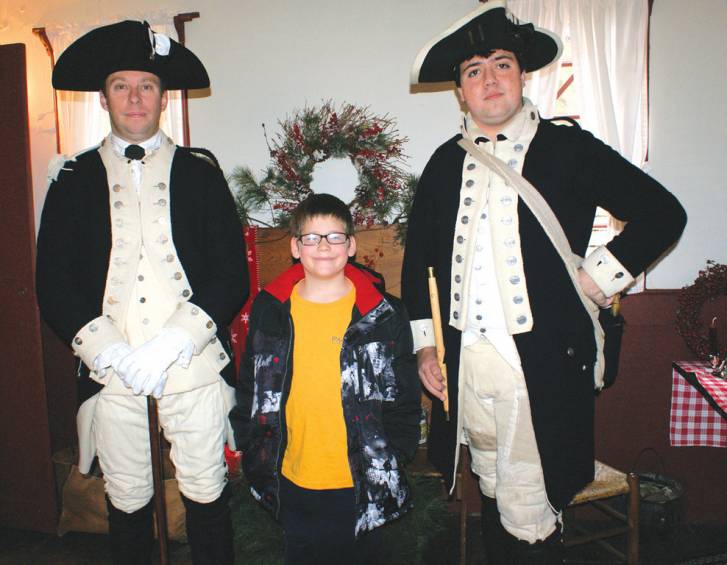 RETURN TRIP: Michael Phillips and Joshua Mason, dressed as a fifer, field questions from 8-year-old Dillon Bombardier, a third grader from George Peters Elementary School. Bombardier had previously visited Joy Homestead, a historical landmark in our city, during a school field trip and wanted to return to see it decorated for the season.