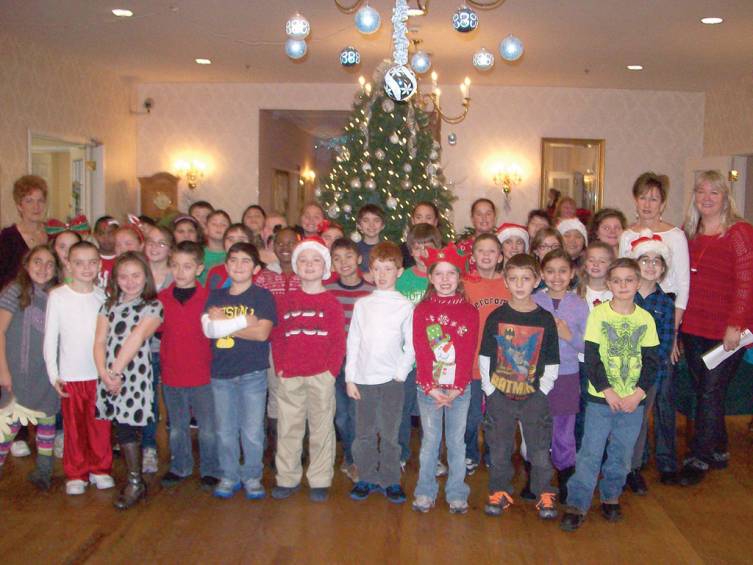 The class poses for a picture in front of the Christmas tree.