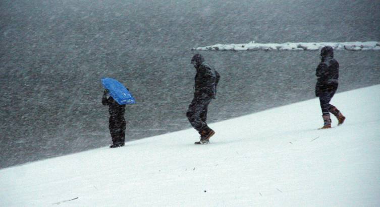 SLEDDING, ANYONE? A sled provides shelter as a family surveys the situation Friday afternoon at Oakland Beach.