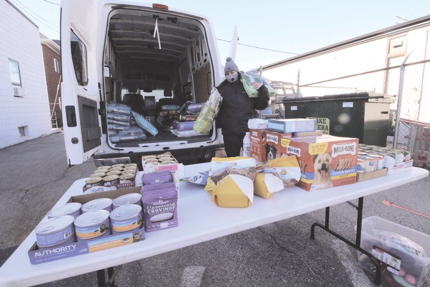 FREE PET FOOD: Madison Lane hoists a bag of pet food during the drive-thru pet pantry hosted Saturday by the Potter League at its clinic on Elm Street off Jefferson Boulevard.