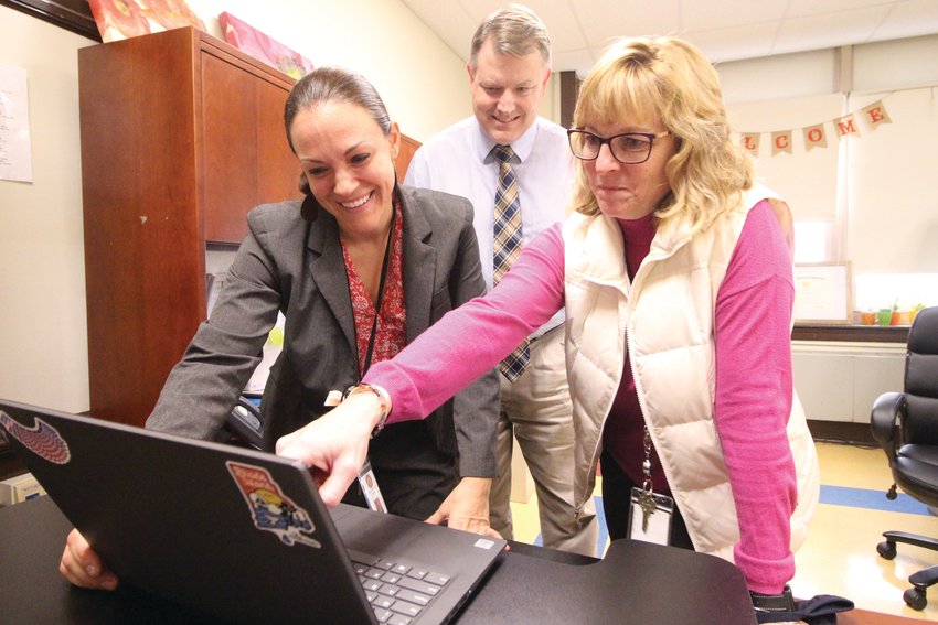 AT HER FINGER TIPS: Lisa Schultz, director of curriculum, accesses test scores on her laptop as assistant superintendent William McCaffrey and elementary school director Patricia Cousineau look on.