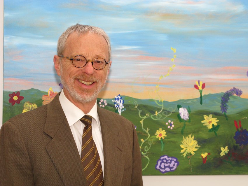 Rev. William A. (Bill) Sterrett stands in front of Amicable Church&rsquo;s &ldquo;Amicable at Worship&rdquo; painting in the church&rsquo;s entry hall. It was painted in a summer of worship service where each worship participant painted the flower they were asked to bring to worship from their garden.