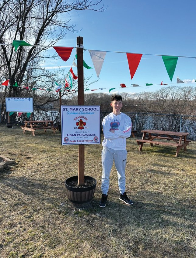 ALL FIXED UP: Eagle Scout Aidan Paplauskas posed for a photo with the freshly scrubbed outdoor classroom sign at St. Mary&rsquo;s School. He built the classroom and erected the sign. The sign was vandalized, but Paplauskas went to work immediately cleaning up the site.