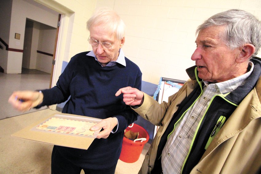 OF INTEREST: Chet Browning, left, past president of the Rhode Island Philatelic Society, looks over a &ldquo;cover&rdquo; brought to the show by Bill Zech of East Greenwich. Zech is looking to sell the stamp collections that are part of his parents&rsquo; estate.