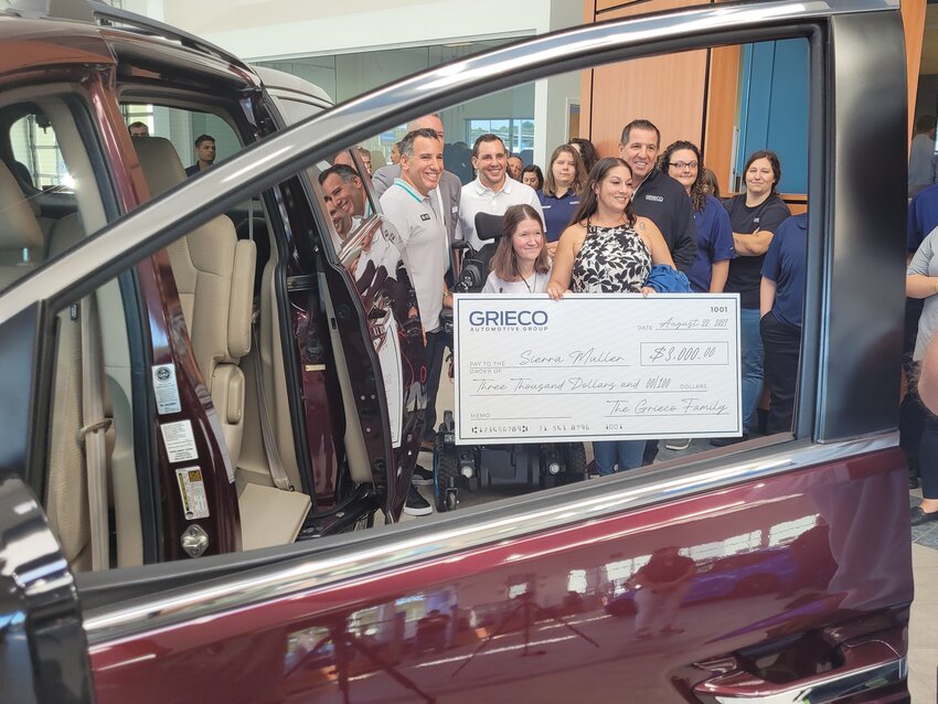 BIG CHECK: Seen through the drivers side window of the family&rsquo;s new van, Robert Grieco, Pre-Owned Director and Grieco Auto Group Partner, presented Ciarra Muller with an oversized ceremonial check for $3,000 &ldquo;for school supplies.&rdquo; Her family joined her in the Grieco Honda showroom, where they also received a Honda Odyssey EX, fully equipped to accommodate Muller&rsquo;s wheelchair.