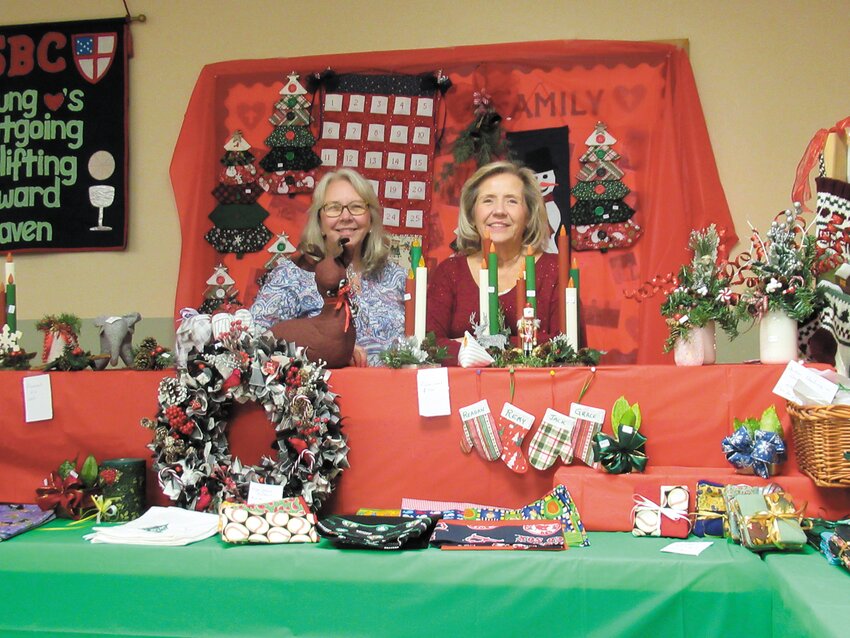 CHRISTMAS CRAFTS: St. Barnabas parishioners Kathy Richardson (left) and Karen Thornton are all smiles inside their booth that featured colorful decorations. (Warwick Beacon photos by Pete Fontaine)