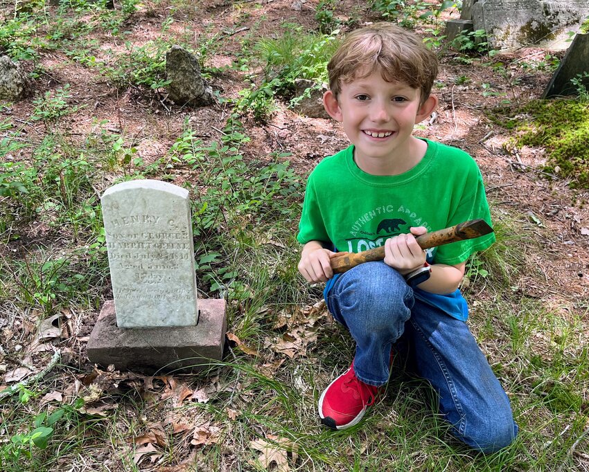 AWARD WINNER: William Trafford, 9, of Warwick poses next to a tombstone he repaired at Maple Root Cemetery in Coventry. (Submitted photo)