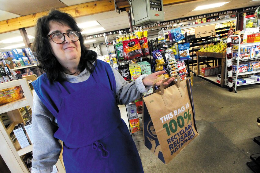 THE PLASTIC ALTERNATIVE: Annie Mechino displays one of the paper bags with handles that Sandy Lane Meat Market offers customers. (Warwick Beacon photo)
