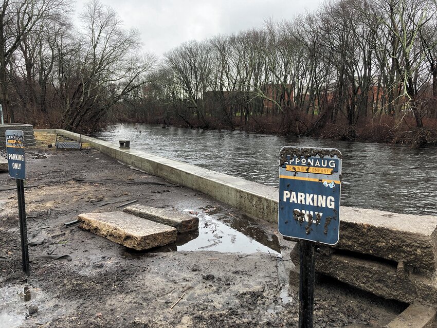 RIVER&rsquo;S STILL RUNNING: The Pawtuxet River flows behind the brewery&rsquo;s parking lot, where the mud from the river&rsquo;s recent flood still remains on formerly submerged signs.
