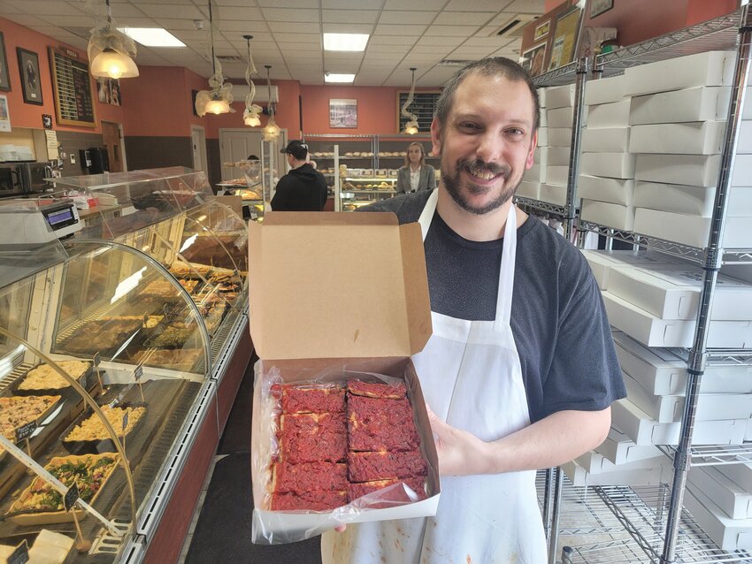 ACQUIRED TASTE: Eric Palmieri, of D. Palmieri&rsquo;s Bakery in Johnston, holds a box of the shop&rsquo;s famous pizza strips. Although one famous pizza reviewer said they&rsquo;re not &ldquo;his thing,&rdquo; if you grew up in the Ocean State, chances are  you&rsquo;ve got strong opinions regarding which bakery serves the best little rectangles. (Beacon Communications photo by Rory Schuler)