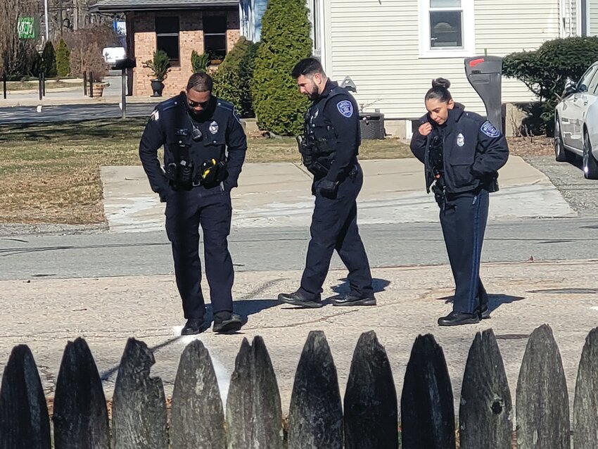 LOOKING FOR EVIDENCE: Warwick patrol officers paced the parking lot of Electronic Alarm Systems, Inc., scanning the macadam for possible evidence. They walked with their heads bowed, eyes focused on the ground. (Warwick Beacon photos)