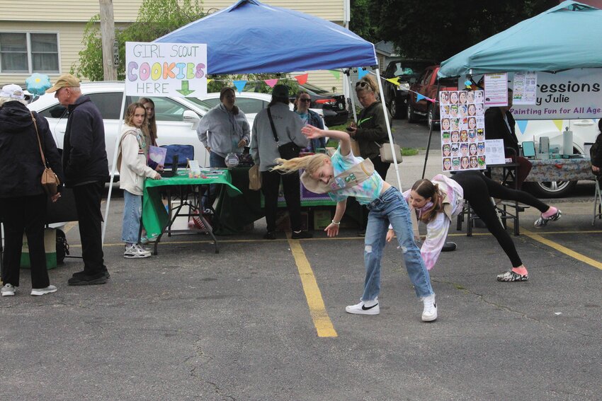 COOKIES AND MORE: Members of Girl Scout Troop 79 manned one of the more than dozen tables at the Conimicut Farmers Market Saturday. Depending on how many boxes of cookies are still available, they will be back this Saturday. In a display of youthful exuberance, Makayla Selwyn and McKenna Frappier do cartwheels in front of their display.
