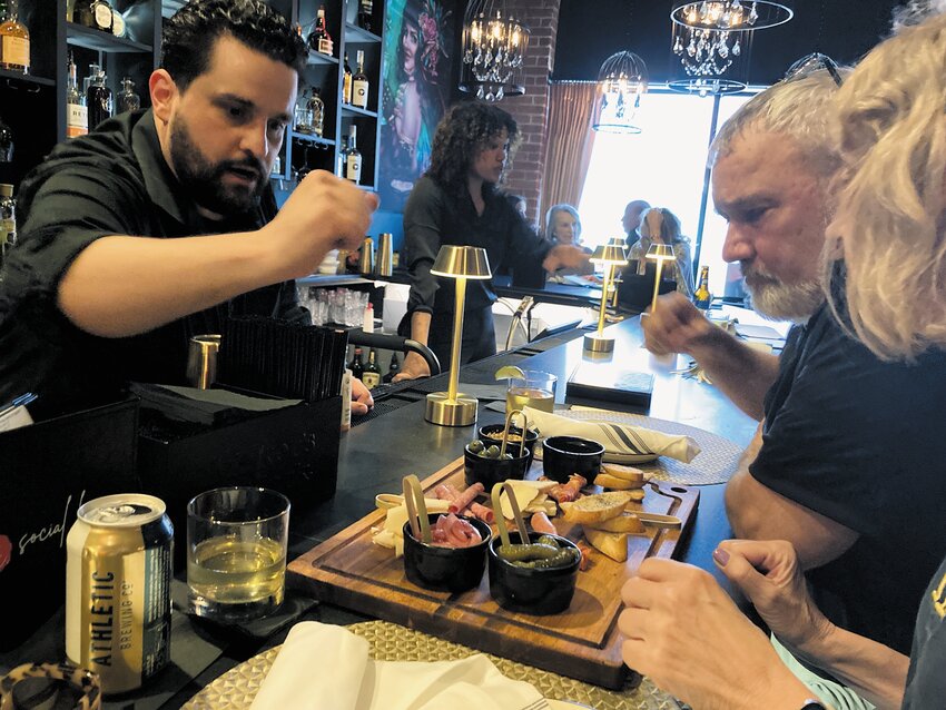 APPETIZERS ARRIVE: Bartender Sergio Lourenco brings out a charcuterie board for patrons Steven Servant and Anne Skelly. (Warwick Beacon photos)