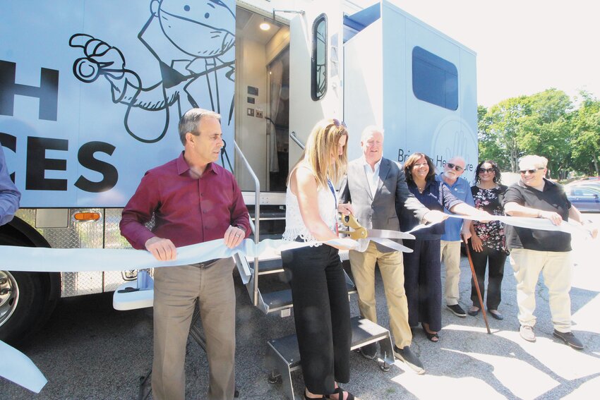 OFFICIALLY OPENED: Pratt, flanked by both mayors, cuts the ribbon, officially inaugurating CCAP’s Mobile Medical Unit.